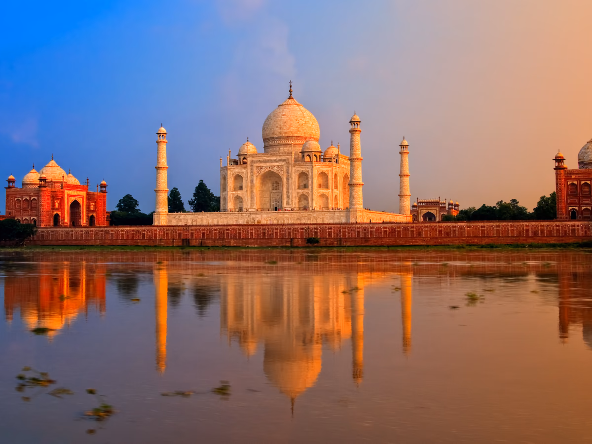 The Taj Mahal glowing beside the Yamuna at sunset.