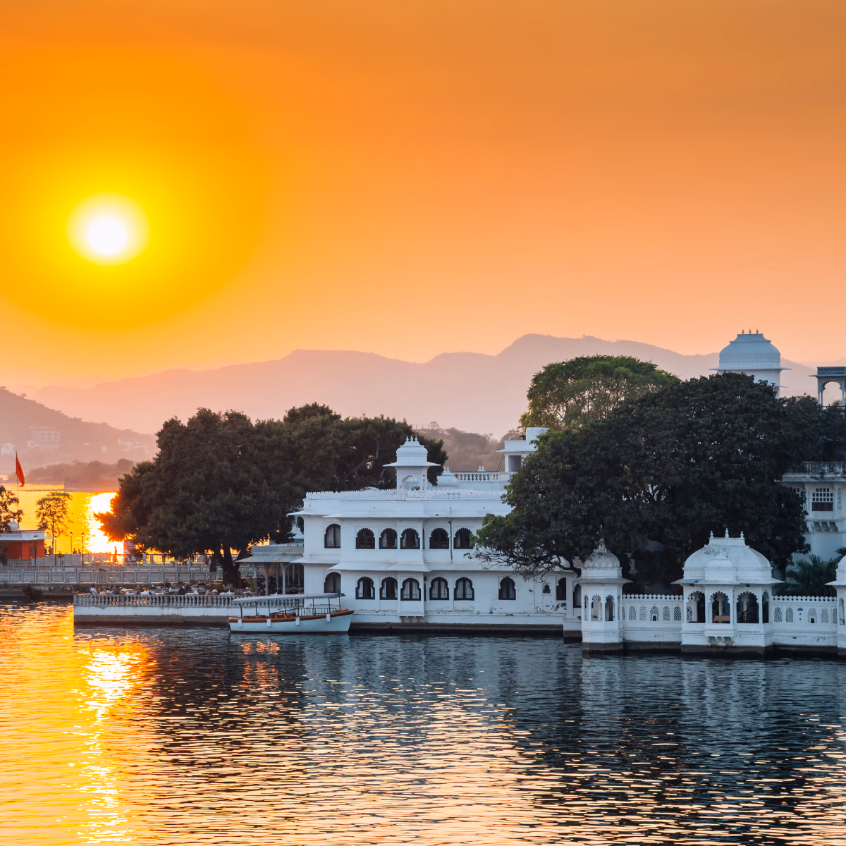 Scena di viaggio a Udaipur's palaces reflected su Lago Pichola a golden ora., tra paesaggio locale e atmosfera del luogo.