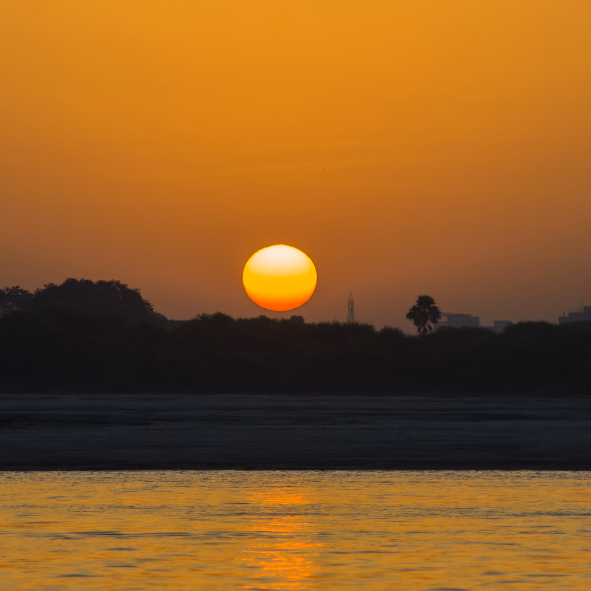 A small boat passing Varanasi's ghats on the Ganga at dawn.