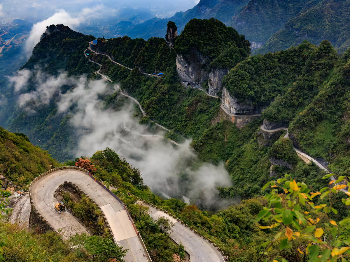 A mountain road climbing toward Pokhara's green hills.