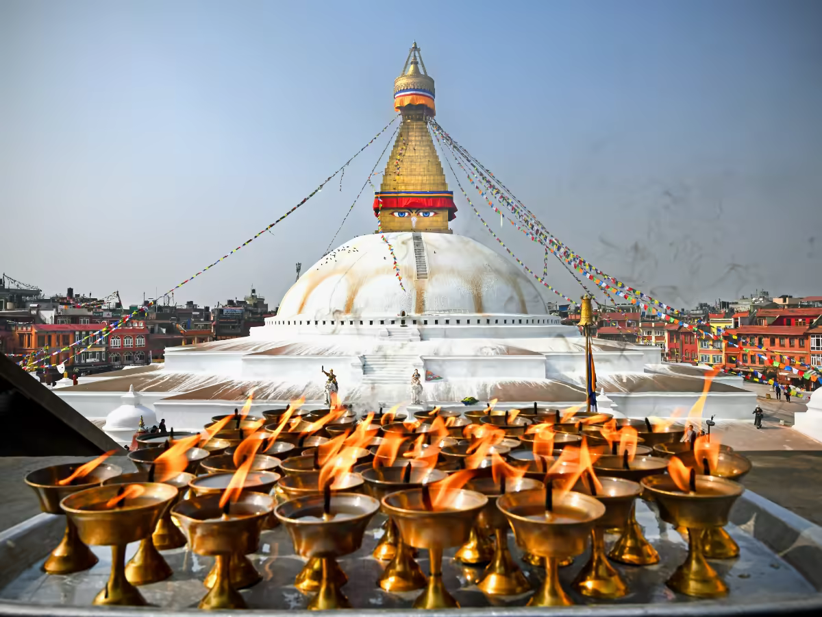 Pilgrims walking around Boudhanath Stupa beneath prayer flags.